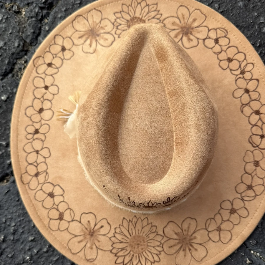 Tan suede wide-brim hat with a hand-burned ring of wildflowers around the brim